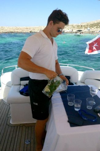 young male yacht steward pouring drinks on board